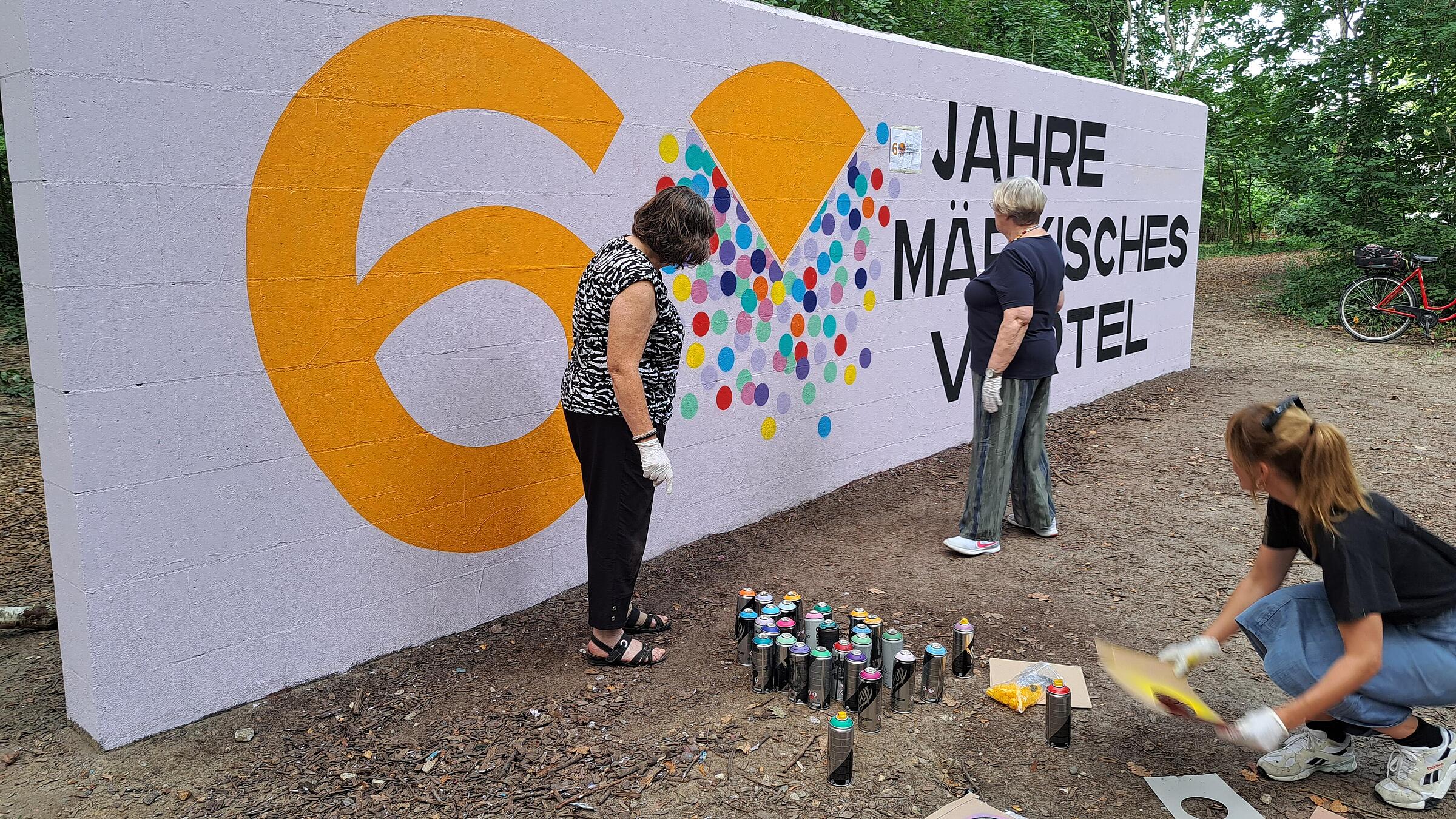 Seniorinnen mit Kkünstlerin Chi Maulbetsch vor der Graffitiwand.