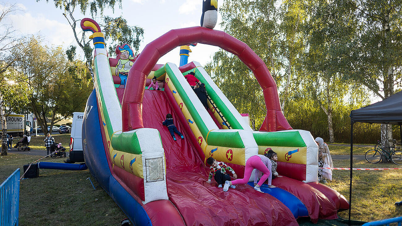 Außenaufnahme zeigt eine aufblasbare Riesenrutsche für Kinder im Sonnenschein. 