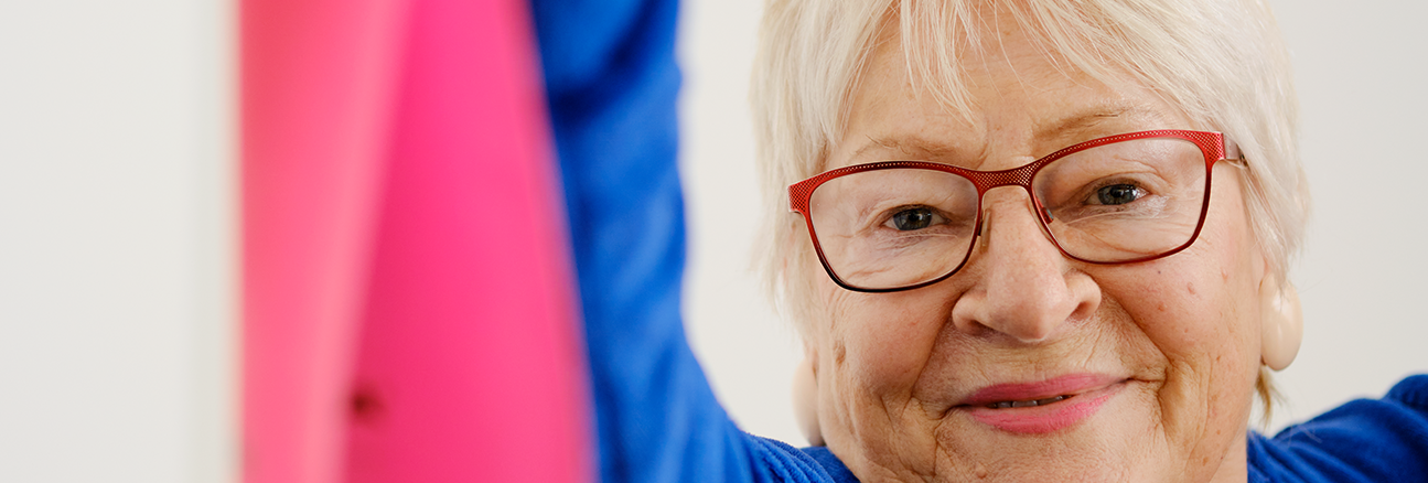 Innenaufnahme zeigt eine Seniorin beim Sport mit einem Dehnband.