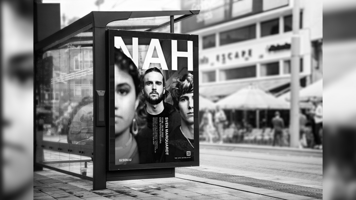 Ausstellungsplakat "Nah" mit jungen Menschen in der Nahaufnahme hängt an einer Bushaltestelle