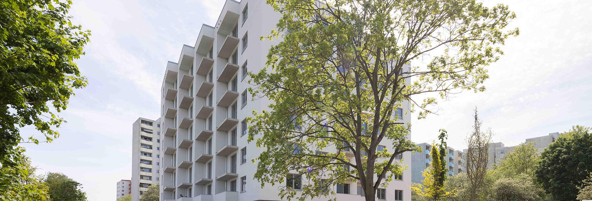 Außenaufnahme aus dem Juni 2022: Der fast fertiggestellte Neubau in der Finsterwalder Straße von der Seite aus fotografiert, vor der Fassade ein Baum. 