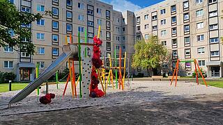 Außenaufnahme zeigt einen eingeweihten Spielplatz mit Rutschenturm, Klatterwand, Schaukel und Geschlicklichkeits- bzw. Balanceparcours auf einer neuen Sandfläche. Am Rutschenturm sind für die Eröffnungsfeier Ballons angebracht.
