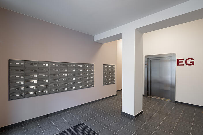 Innenaufnahme: Eingangsbereich für Mieter*innen im Wilhelmsruher Damm 142, Lift und Briefkästen.