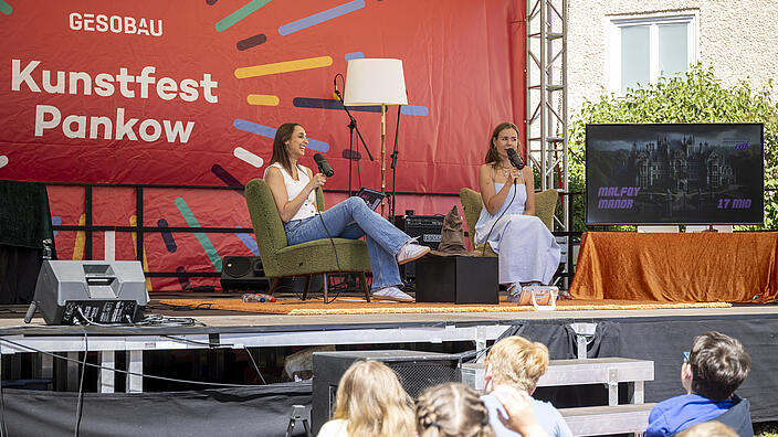 Zwei Frauen nehmen einen Live-Podcast auf der Kunstfest-Bühne auf.