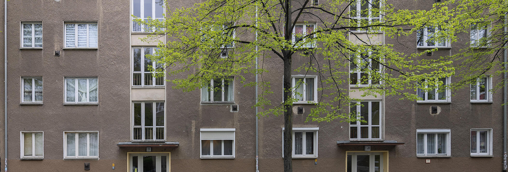 straßenseitige Fassade eines fünfstöckigen Wohnhauses vor Modernisierung