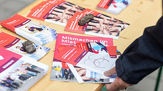 Außenaufnahme zeigt Informationsmaterialien zu den Mieterratswahlen 2022 der GESOBAU auf einer Holzbank liegend.