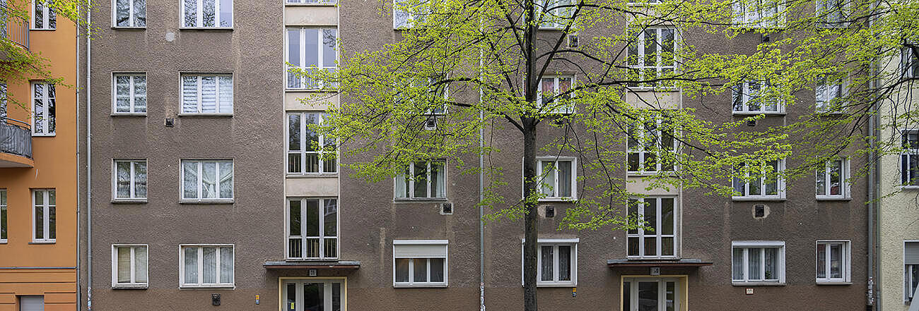 straßenseitige Fassade eines fünfstöckigen Wohnhauses vor Modernisierung.