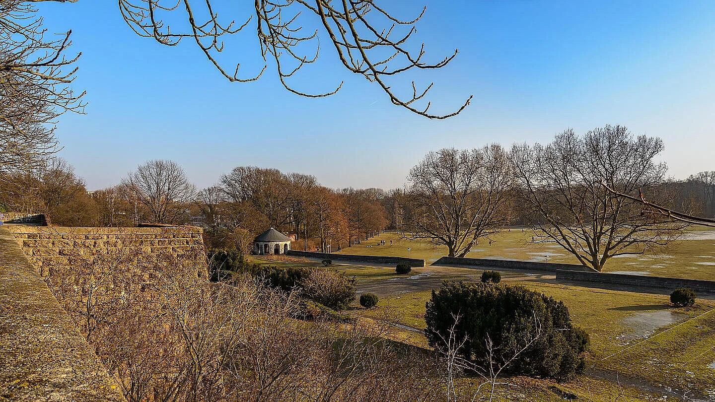 Die Außenaufnahme zeigt eine winterliche Landschaftsszene im Schillerpark in Berlin-Wedding mit kahlen Bäumen und vereinzelt vereisfächten Flächen auf der Wiese.