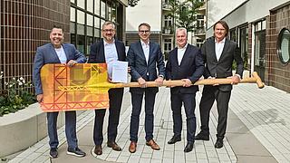 Die sieben Geschäftsführer und Vorstände der landeseigenen Wohnungsbaugesellschaften halten symbolisch einen großen Spaten in den Händen.