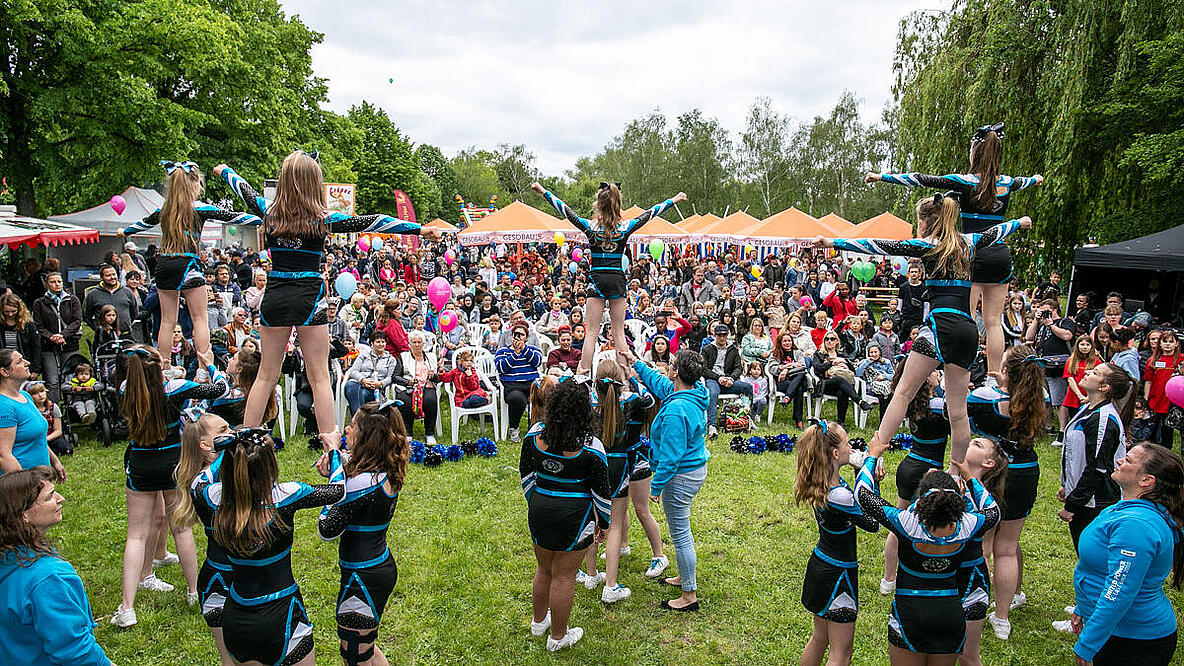 Festwiese mit Cheerleaderinnen im Vordergrund un einem Publikum im Hintergrund.