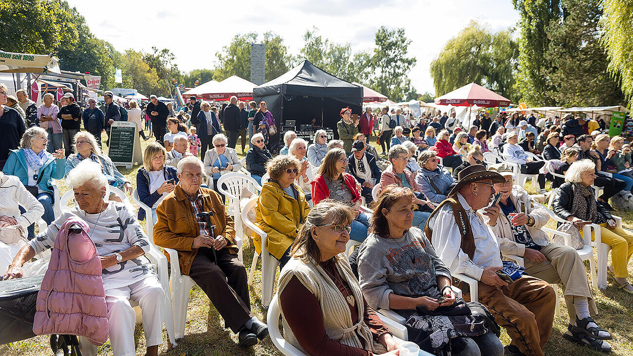 Aufnahme des sitzenden Publikums des Begegnungsfestes 2024 im Sonnenschein. 