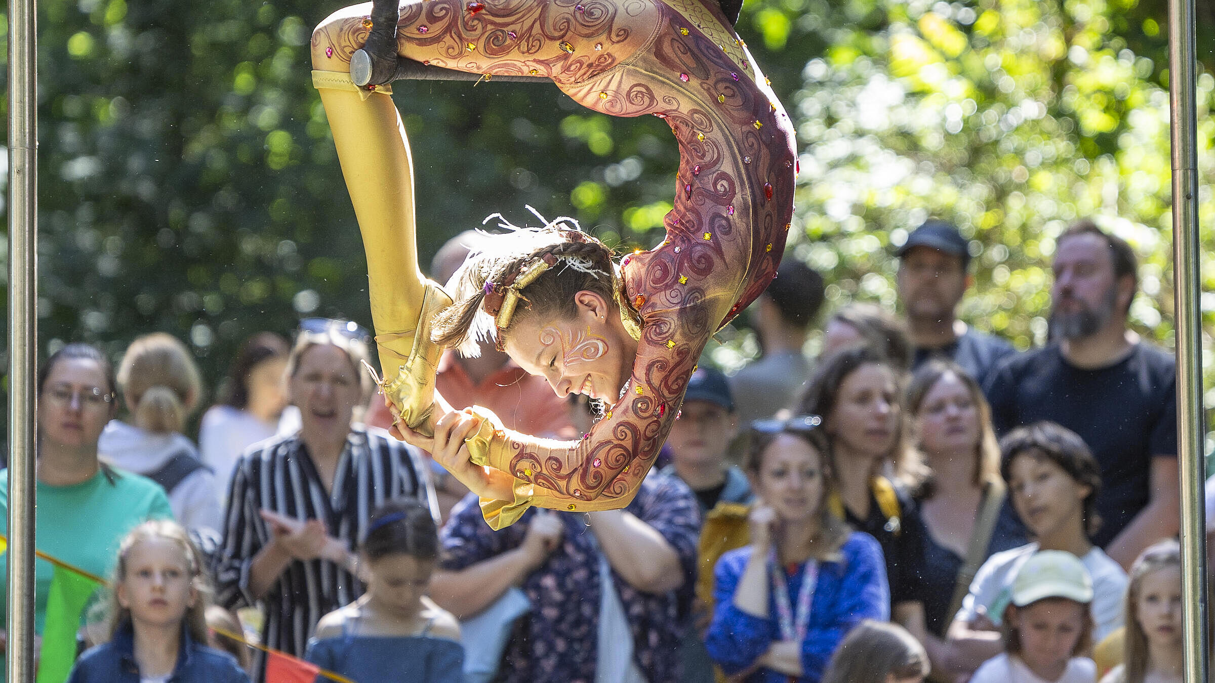 Foto zeigt eine Akrobatin des Kinderzirkus contraire bei einer Figur an einem Seil, im Hintergrund eine Menge staunender Kinder.