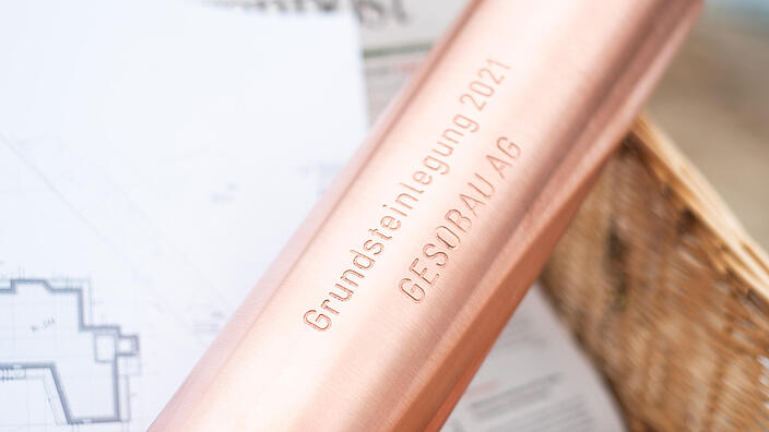 Foto zeigt eine Kupferrolle-Schatulle mit der Aufschrift "Grundsteinlegung, Gesobau AG"