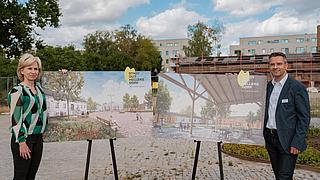 Heike Wessoly und Daniel Kautz stehen neben den Visualisierungen des Stadtgut Hellersdorf